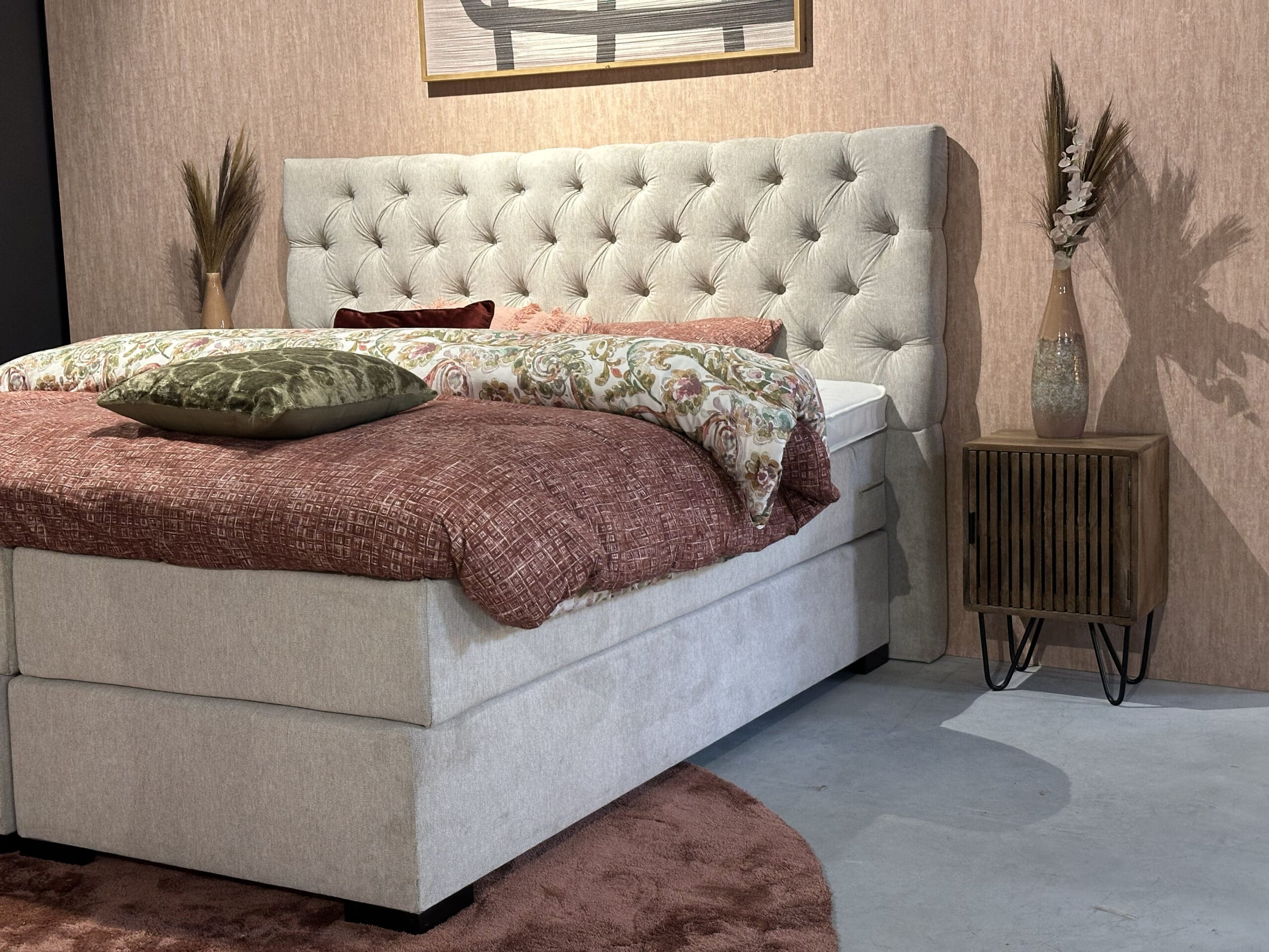 Boxspring bed met beige hoofdbord en gebloemd dekbed