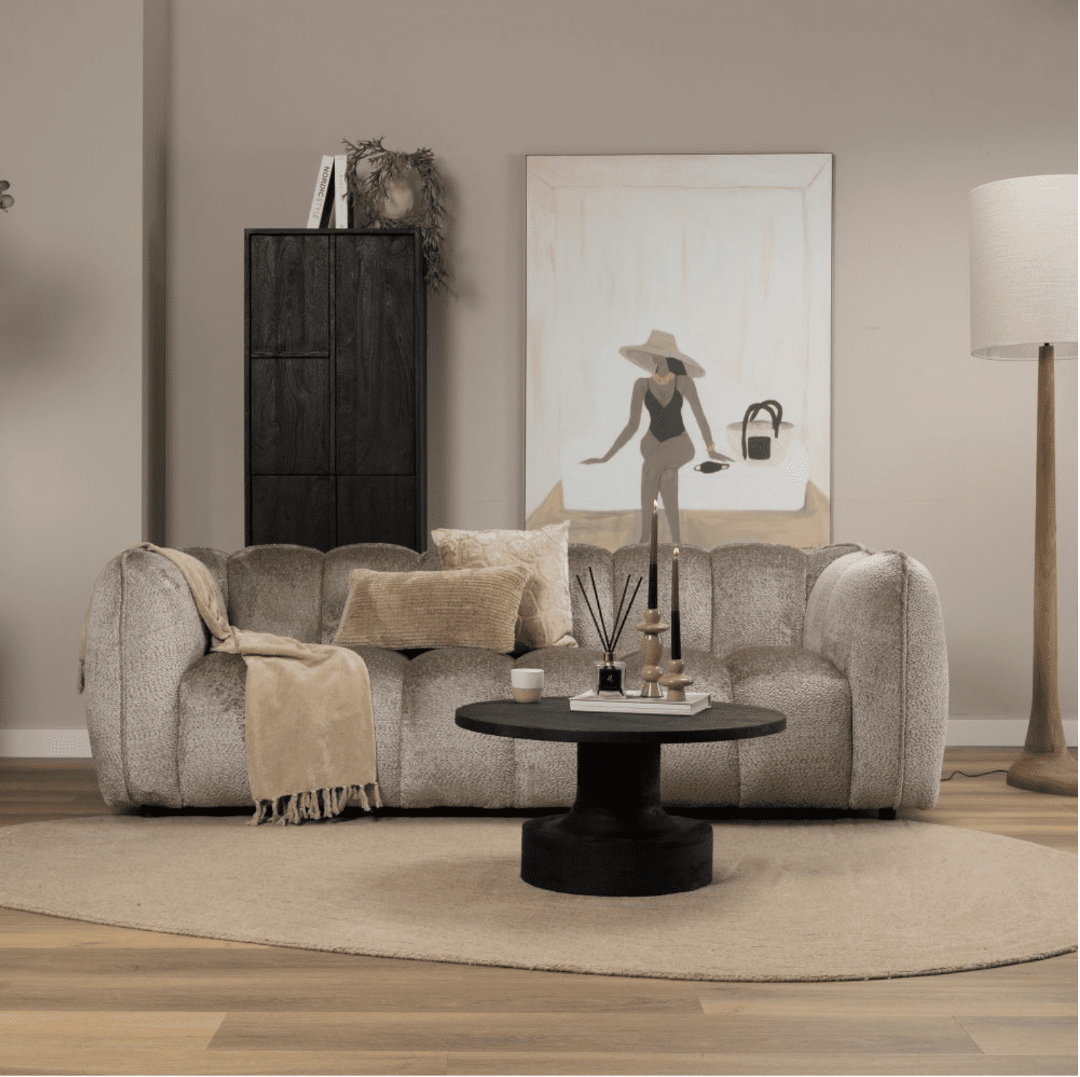 Beige gestoffeerde bank met kunstwerk, kaarsen en kussens