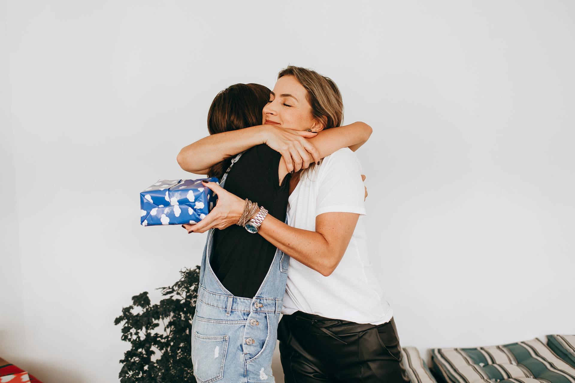 Volwassen dochter knuffelt haar moeder met een moederdag-cadeau in haar hand