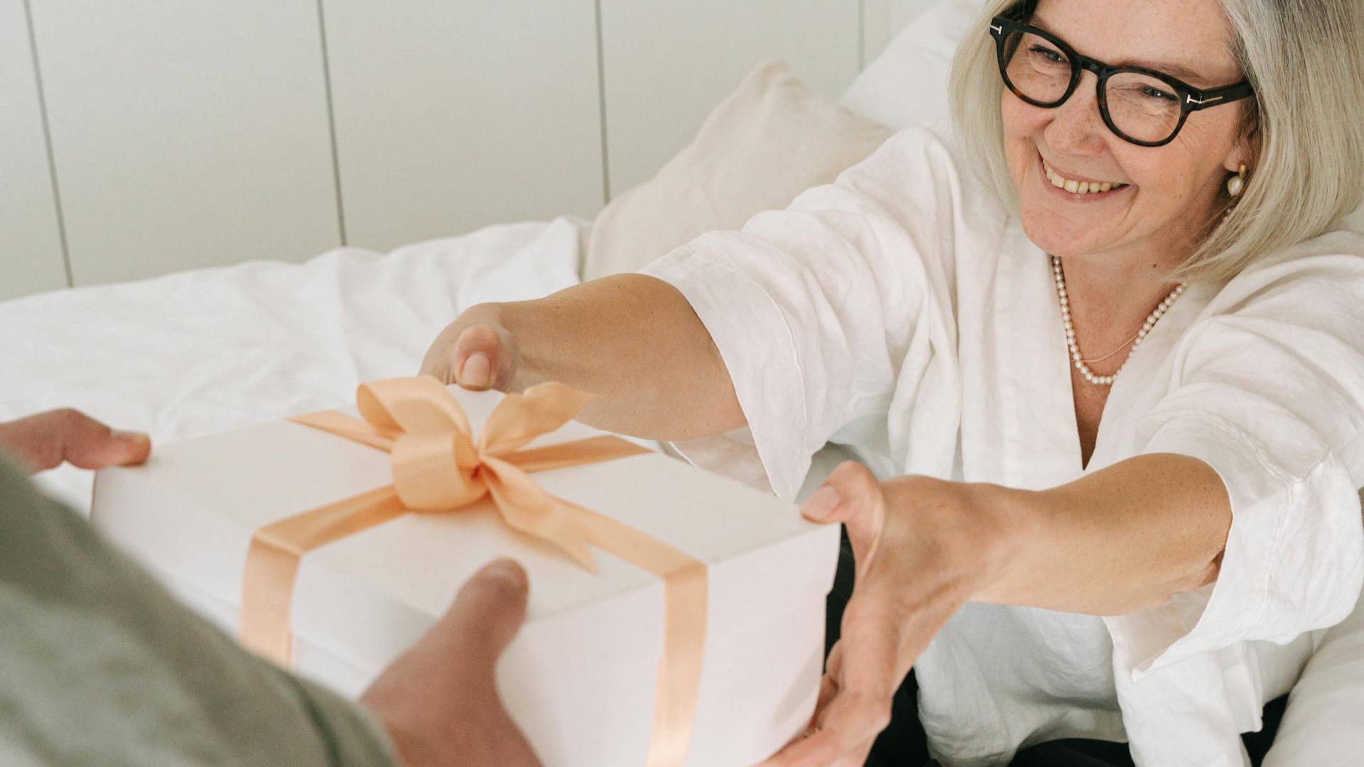 Oudere moeder ontvangt een mooi ingepakt cadeau op moederdag